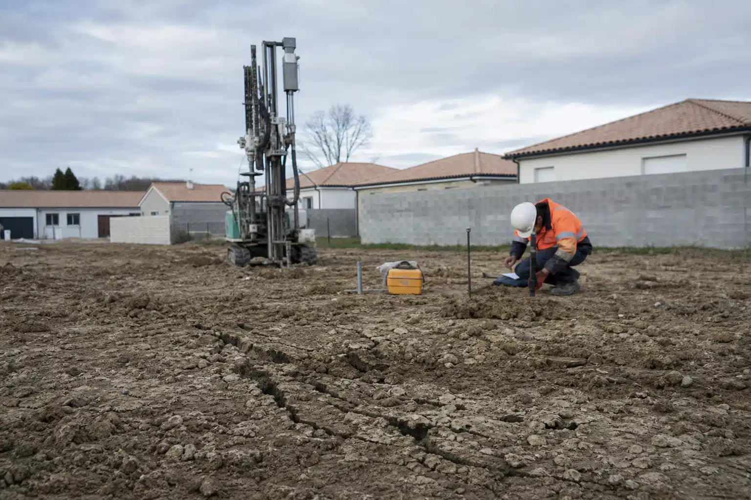 Ouvrier en gilet orange près d'un engin de forage